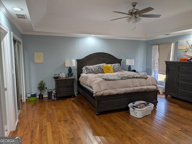 bedroom with ornamental molding, a raised ceiling, and hardwood / wood-style floors