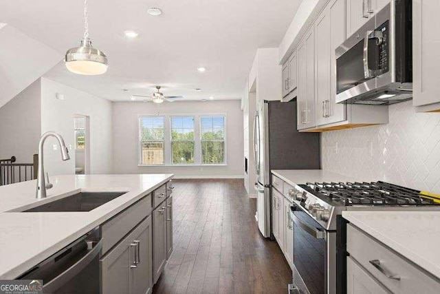 kitchen featuring stainless steel appliances, sink, gray cabinetry, and decorative light fixtures