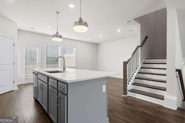 kitchen with sink, dark hardwood / wood-style floors, gray cabinets, pendant lighting, and a kitchen island with sink