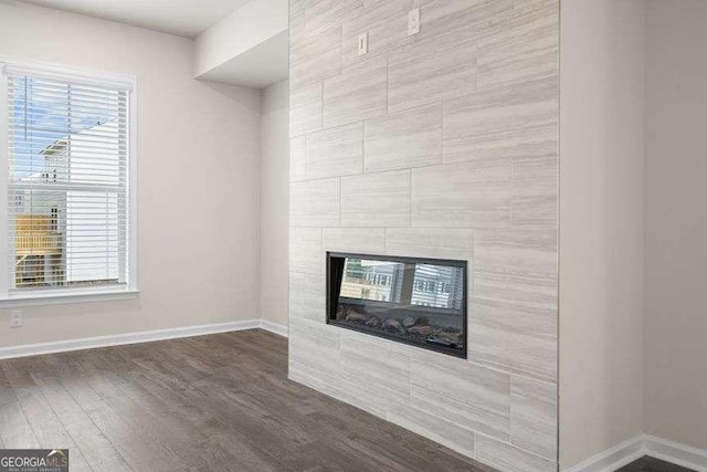 unfurnished living room with dark wood-type flooring and a fireplace