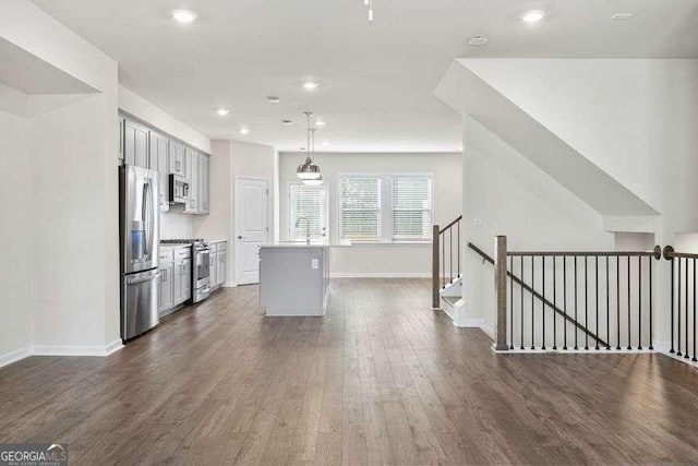 kitchen with dark hardwood / wood-style flooring, hanging light fixtures, stainless steel appliances, and a center island