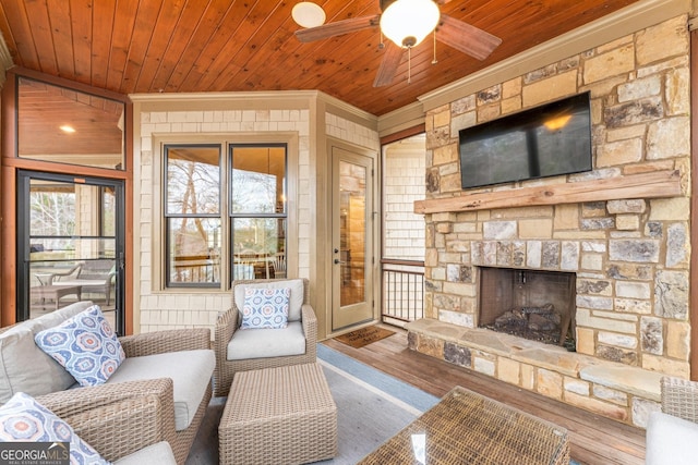 living room with crown molding, ceiling fan, wood-type flooring, a stone fireplace, and wooden ceiling