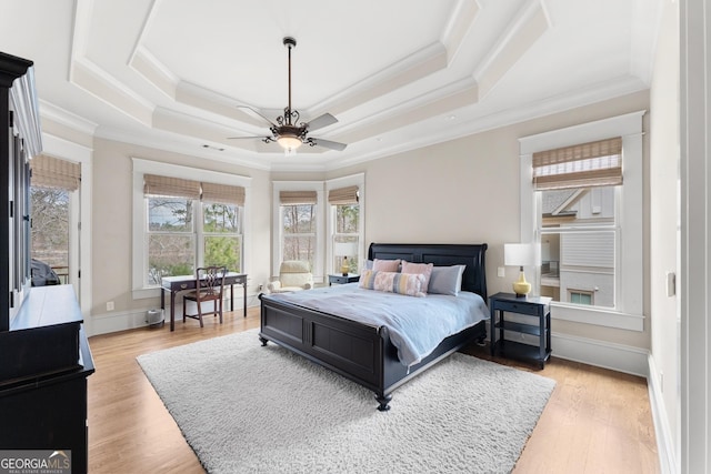 bedroom featuring crown molding, a raised ceiling, and light wood-type flooring