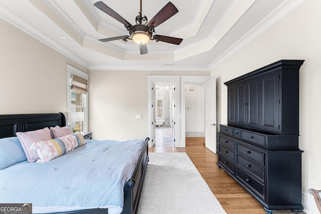 bedroom with hardwood / wood-style flooring, ceiling fan, crown molding, and a raised ceiling