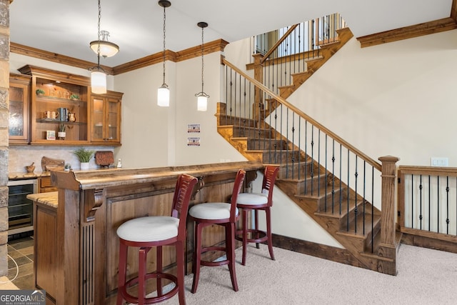 bar with beverage cooler, backsplash, hanging light fixtures, light colored carpet, and crown molding