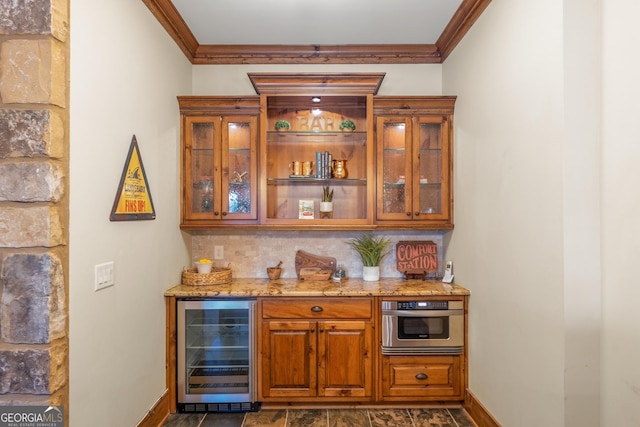 bar featuring tasteful backsplash, oven, beverage cooler, ornamental molding, and light stone counters