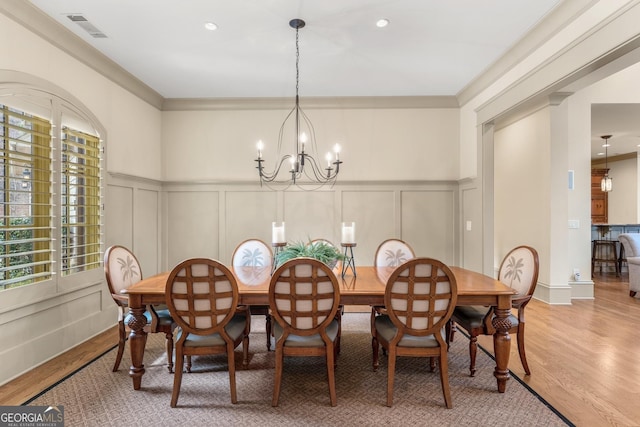 dining area with crown molding, a healthy amount of sunlight, wood-type flooring, and a chandelier