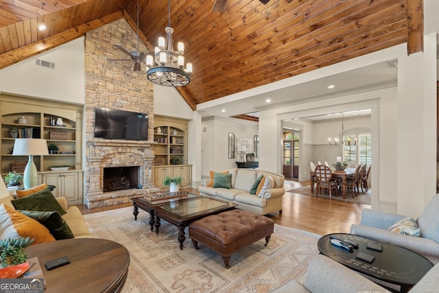 living room with a stone fireplace, an inviting chandelier, built in features, wooden ceiling, and light wood-type flooring