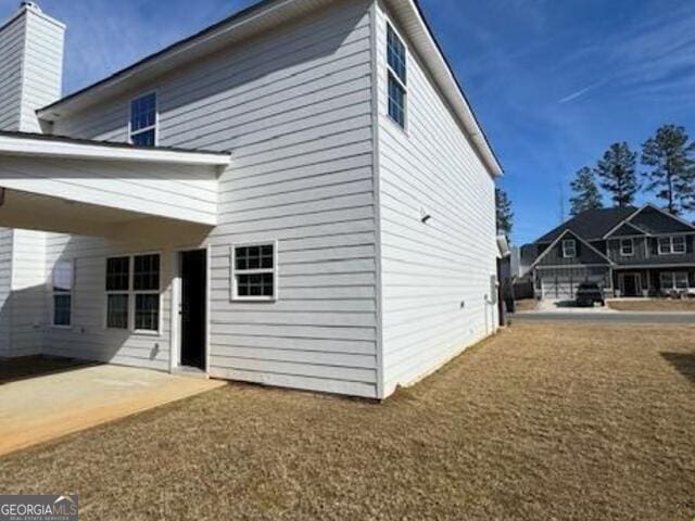 view of property exterior with a yard and a patio area