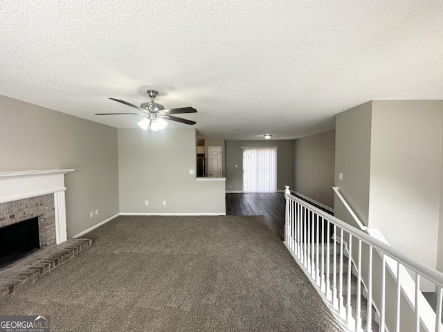 1202 Grove Trail Pass, Douglasville, GA 30134 - unfurnished living room with ceiling fan, dark colored carpet, a fireplace, and a textured ceiling