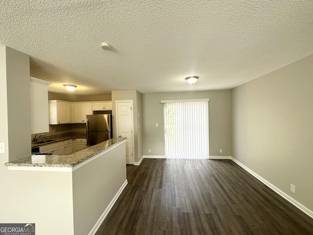 1202 Grove Trail Pass, Douglasville, GA 30134 - kitchen with freestanding refrigerator, dark wood finished floors, white cabinetry, light stone countertops, and a peninsula