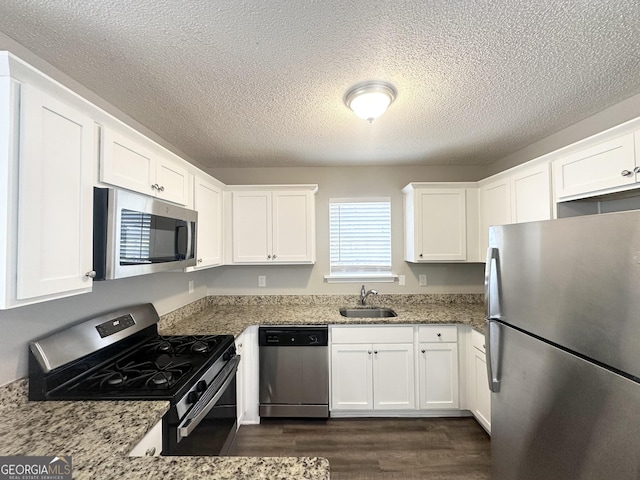 1202 Grove Trail Pass, Douglasville, GA 30134 - kitchen featuring appliances with stainless steel finishes, dark wood-style floors, white cabinetry, a textured ceiling, and light stone counters