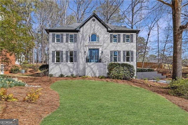 colonial inspired home with stucco siding and a front yard