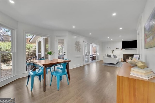 dining area featuring plenty of natural light, wood finished floors, and a glass covered fireplace