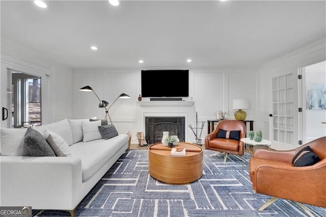 living area featuring a fireplace, ornamental molding, a decorative wall, and recessed lighting