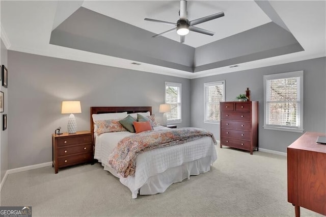 bedroom with light carpet, a ceiling fan, baseboards, ornamental molding, and a raised ceiling