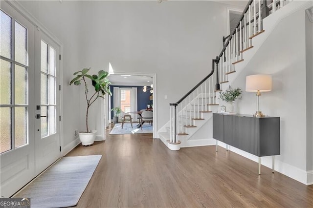 foyer with baseboards, stairs, a high ceiling, and wood finished floors