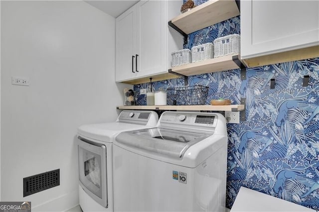 washroom featuring visible vents, washer and clothes dryer, and cabinet space