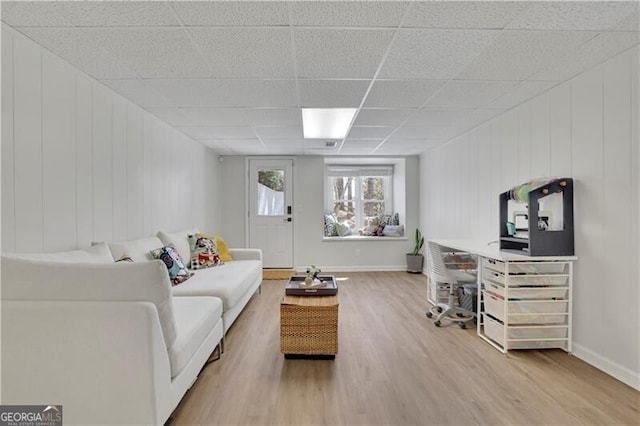 living room featuring baseboards, a drop ceiling, and wood finished floors