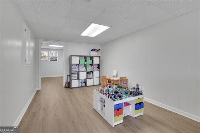 playroom with a paneled ceiling, baseboards, and wood finished floors