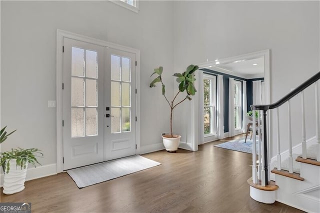 foyer entrance featuring stairs, french doors, wood finished floors, and baseboards