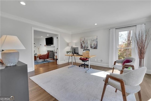 office featuring crown molding, a fireplace, and wood finished floors