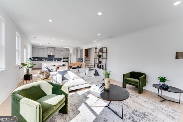 living area featuring light wood finished floors, crown molding, baseboards, stairway, and recessed lighting