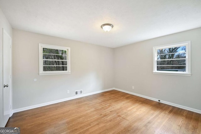 unfurnished room with a healthy amount of sunlight, light hardwood / wood-style flooring, and a textured ceiling