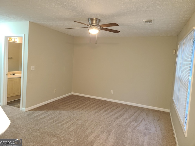 carpeted spare room featuring ceiling fan, sink, and a textured ceiling