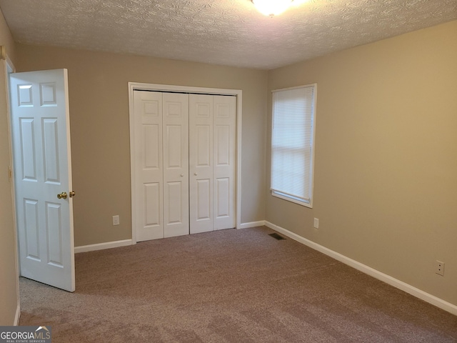 unfurnished bedroom featuring light colored carpet, a closet, and a textured ceiling