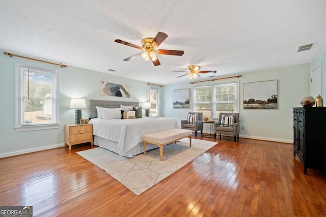 bedroom featuring multiple windows, light hardwood / wood-style flooring, and a textured ceiling