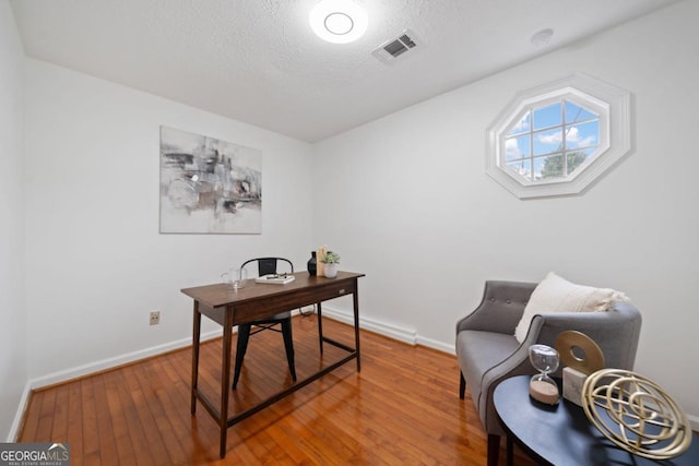 home office with wood-type flooring and a textured ceiling