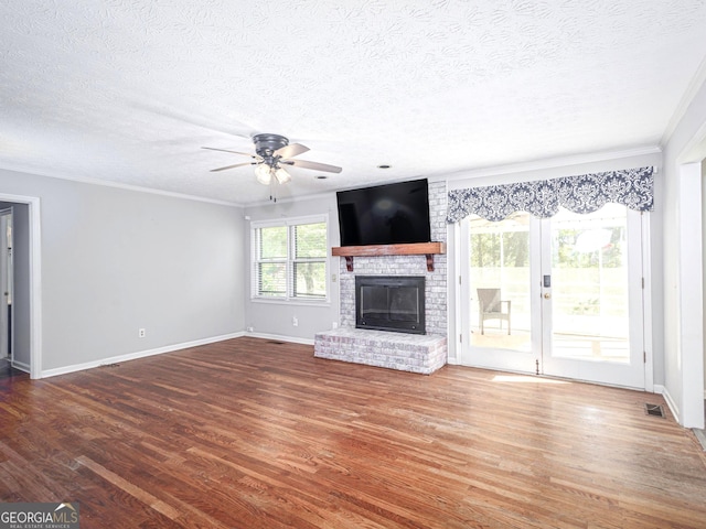 unfurnished living room with hardwood / wood-style flooring, crown molding, a brick fireplace, and ceiling fan