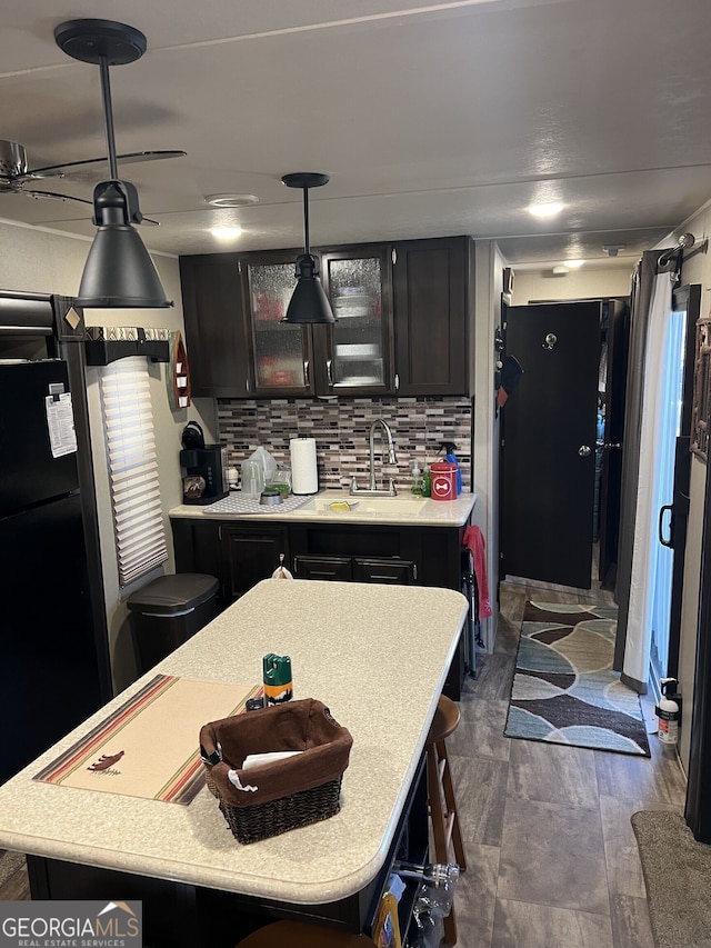 kitchen with a breakfast bar, pendant lighting, tasteful backsplash, sink, and a center island