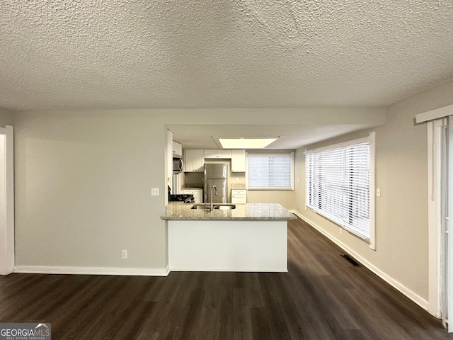 kitchen featuring white cabinetry, appliances with stainless steel finishes, dark hardwood / wood-style flooring, and kitchen peninsula