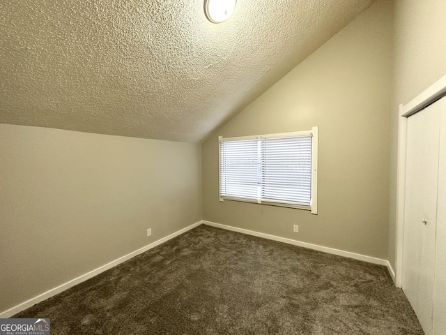 bonus room featuring dark carpet, vaulted ceiling, and a textured ceiling