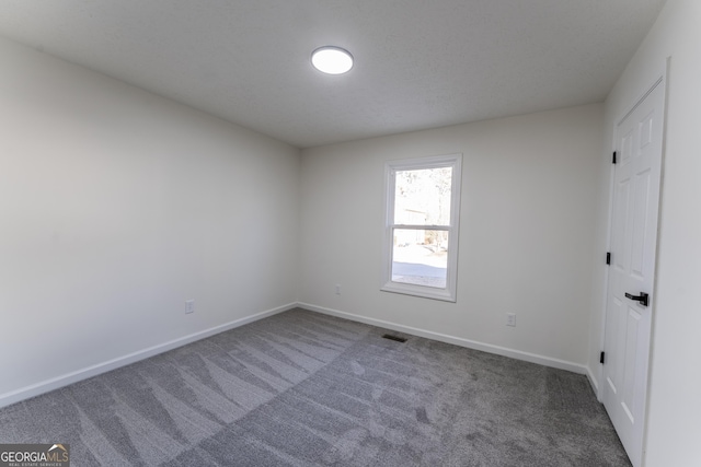 unfurnished bedroom featuring a textured ceiling and dark carpet