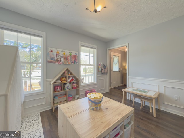 playroom with dark wood-type flooring and a textured ceiling