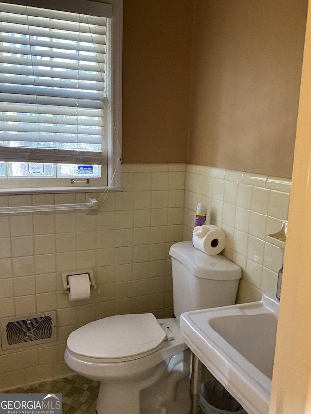 bathroom featuring tile walls and toilet