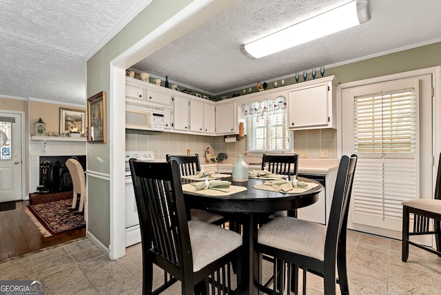 dining room featuring a fireplace, ornamental molding, and a textured ceiling