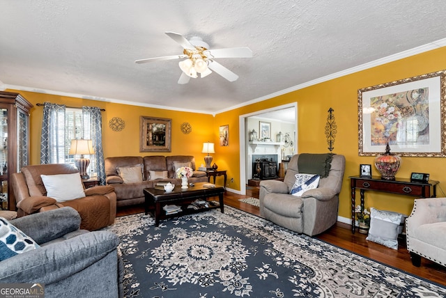 living room featuring dark hardwood / wood-style flooring, ceiling fan, ornamental molding, and a textured ceiling