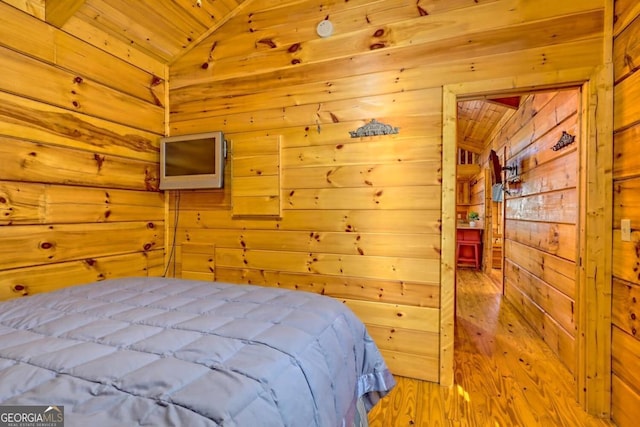 bedroom with lofted ceiling, wood ceiling, light hardwood / wood-style flooring, and wood walls