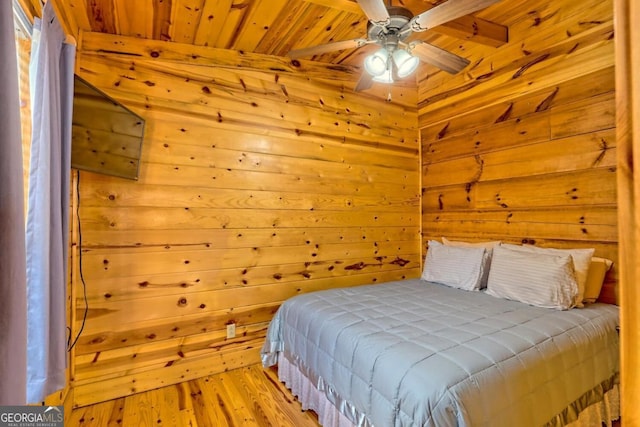 bedroom with ceiling fan, light hardwood / wood-style floors, wood ceiling, and wood walls