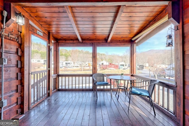 sunroom with a mountain view, beam ceiling, and wooden ceiling