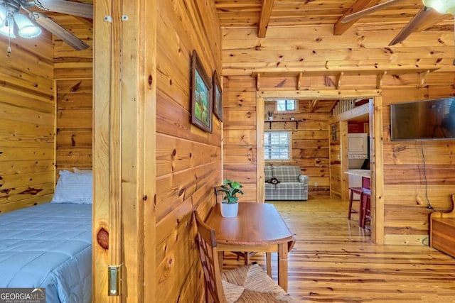 bedroom with wooden walls, light hardwood / wood-style floors, beam ceiling, and wooden ceiling