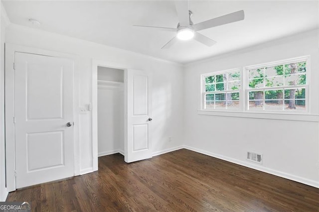 unfurnished bedroom featuring dark wood-style flooring, a ceiling fan, visible vents, baseboards, and a closet