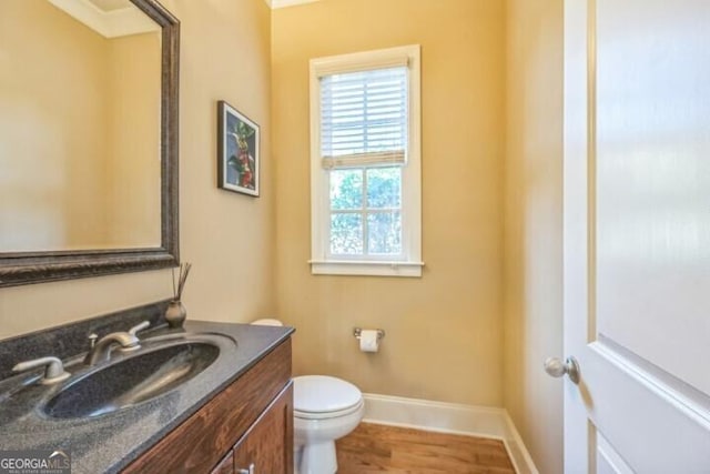 bathroom with hardwood / wood-style flooring, toilet, and vanity