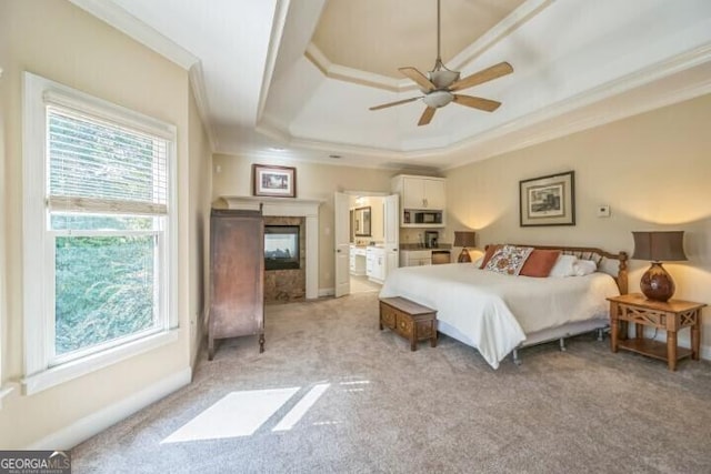 bedroom with a tray ceiling, ornamental molding, light carpet, and a premium fireplace