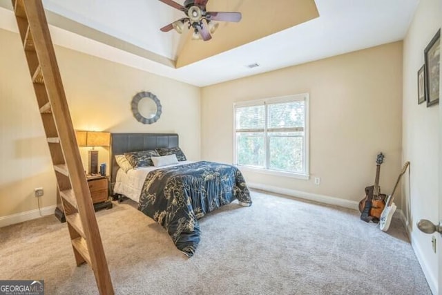 carpeted bedroom featuring a tray ceiling and ceiling fan