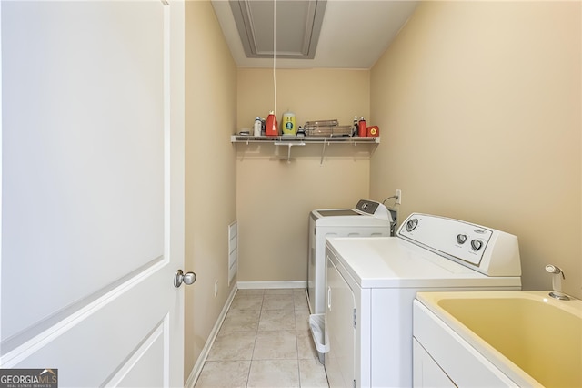 washroom featuring washing machine and dryer, sink, and light tile patterned floors